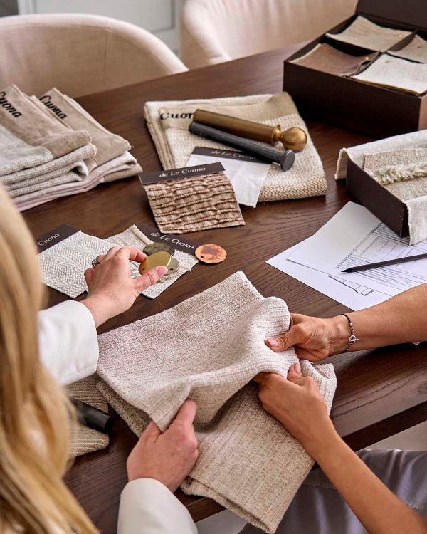 Two people examining fabric swatches on a table with design documents.
