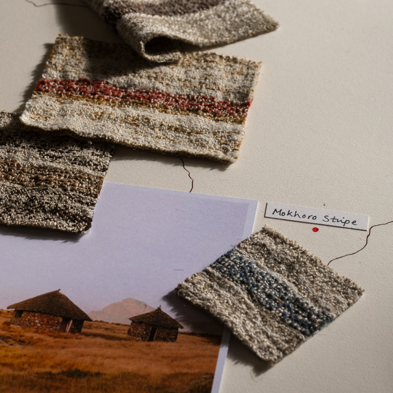 Textured fabric swatches on a surface with a landscape photo and label.