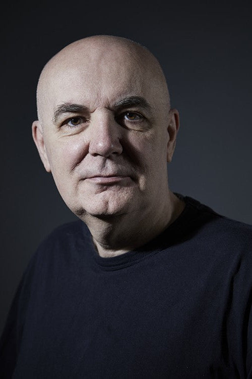 Bald man wearing a dark shirt against a black background