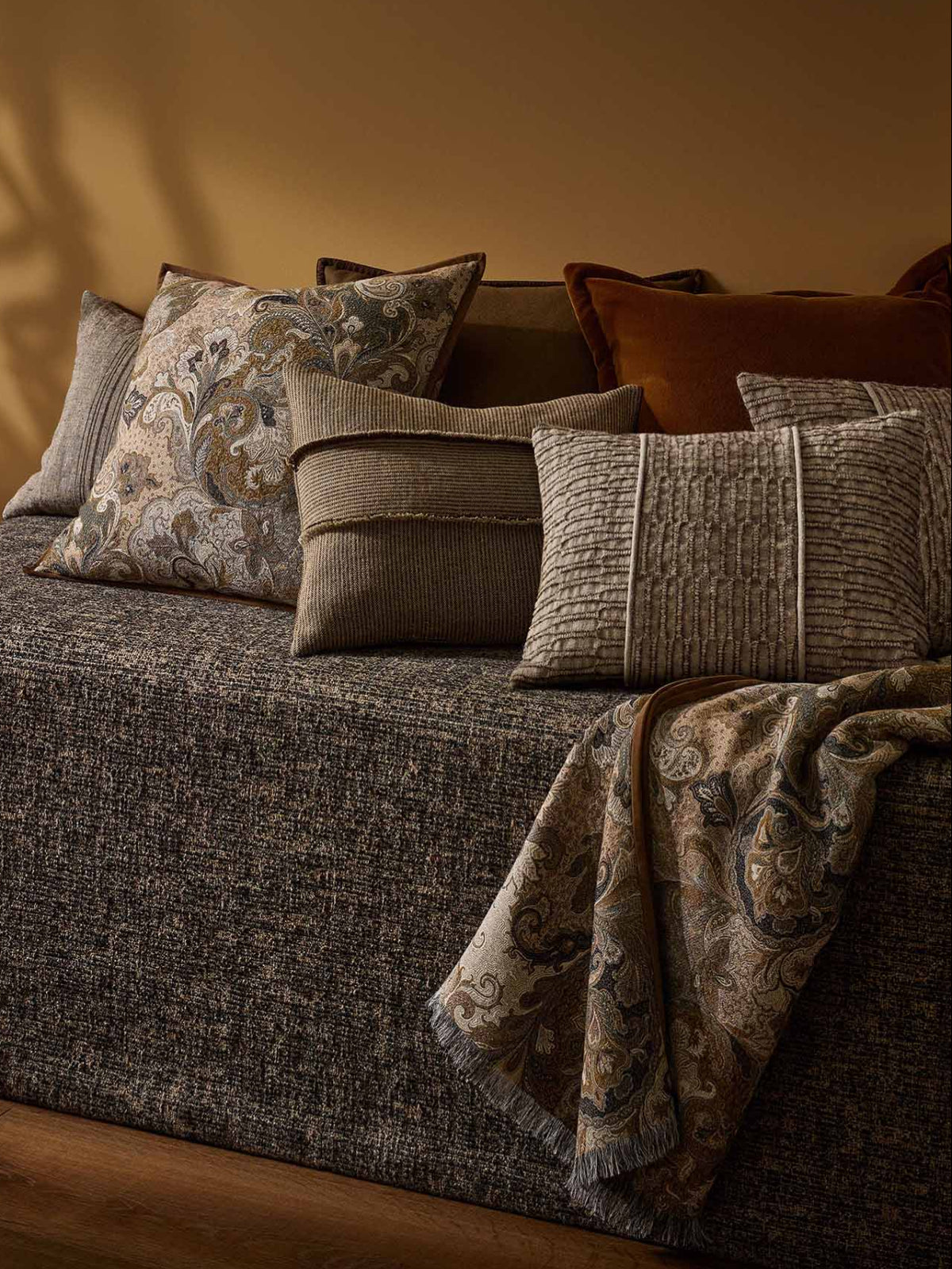 Gray sofa with patterned cushions against a warm-toned wall.