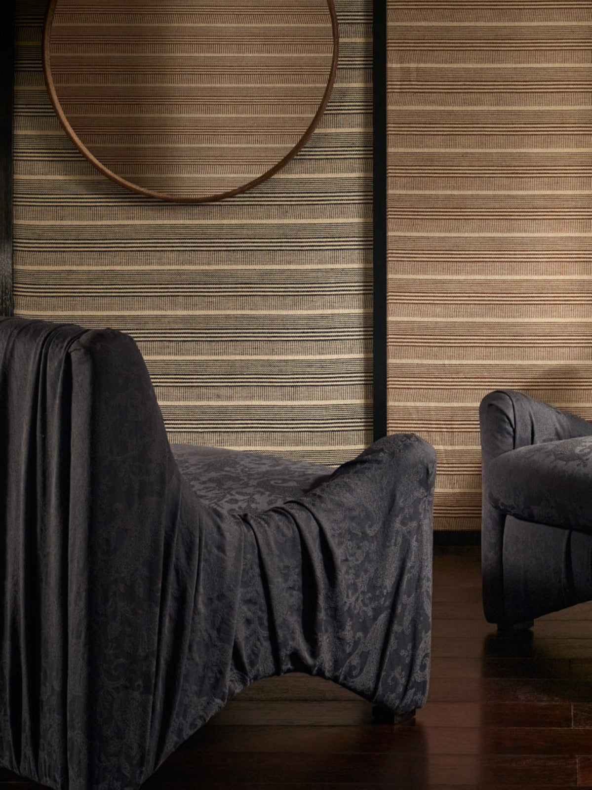 Dark gray armchair with a pillow against a wooden paneled wall.