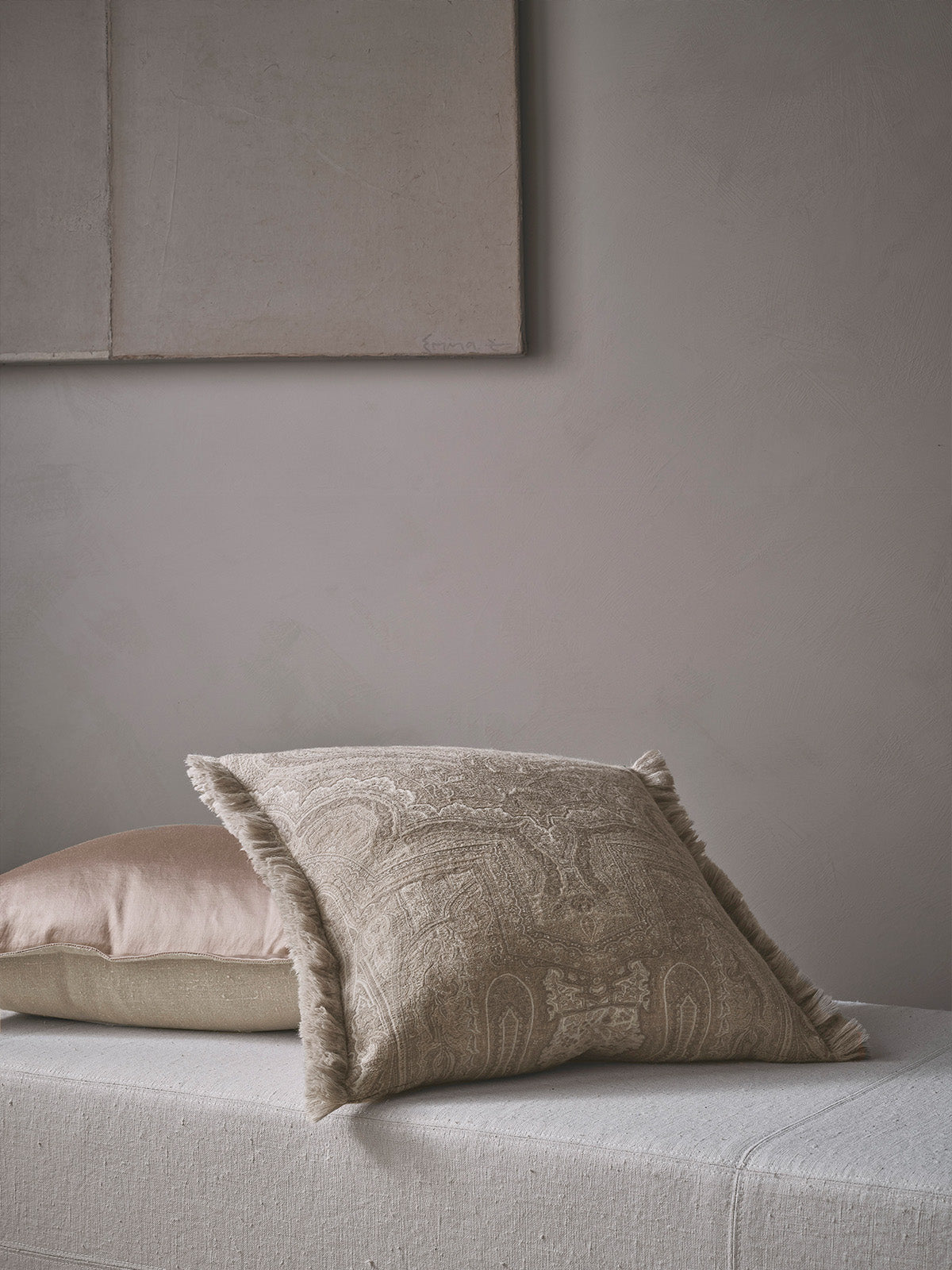 Textured beige cushion on a light grey sofa against a neutral wall.