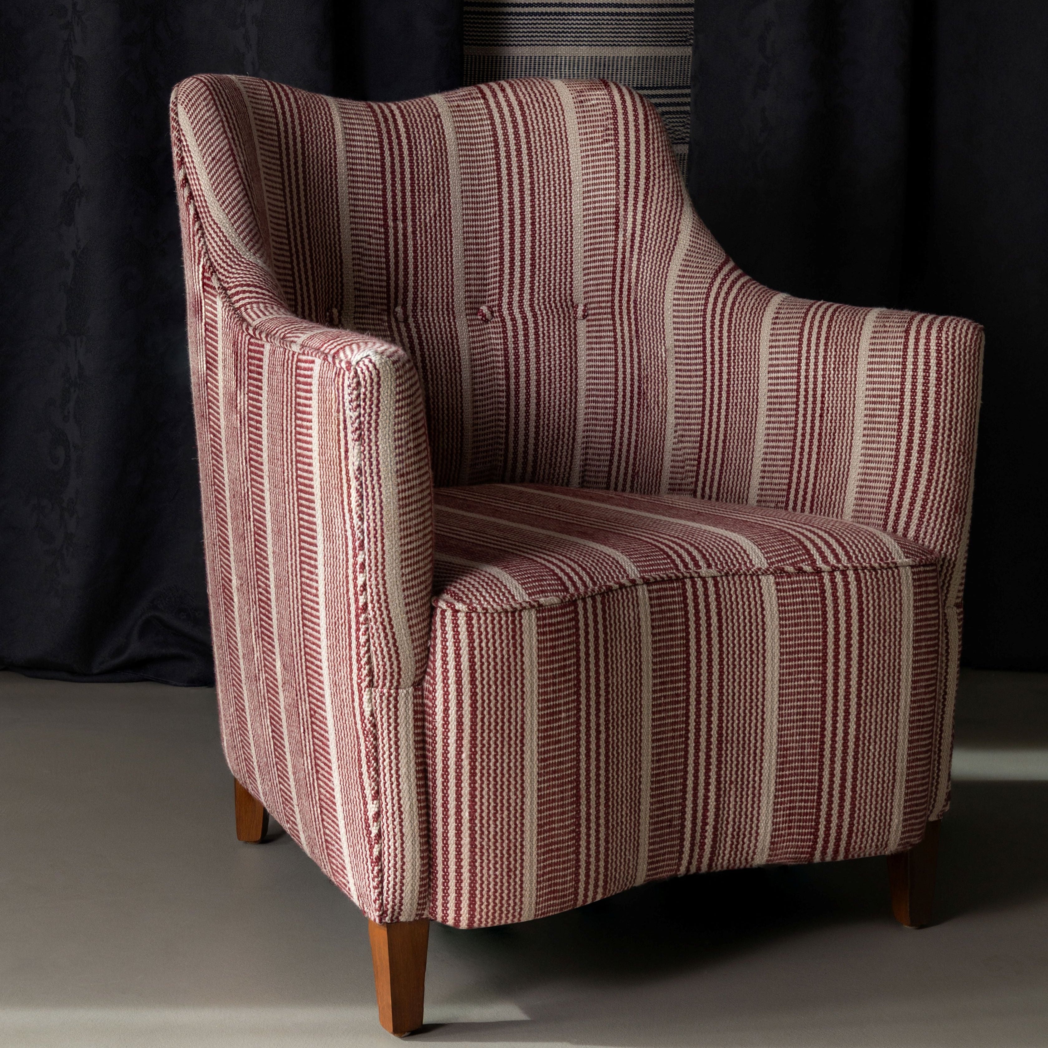 Striped armchair against a dark curtain backdrop