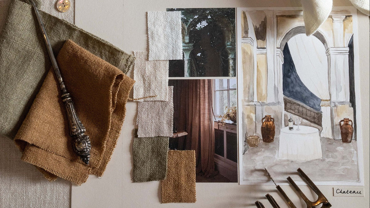 A styled interior design mood board featuring linen fabric swatches in beige, brown, and olive green, a dark metal candlestick, architectural art prints, and decorative gold-toned metal accessories on a neutral fabric background.