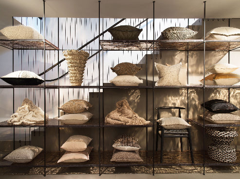 Display of pillows and decorative items on a metal shelving unit.