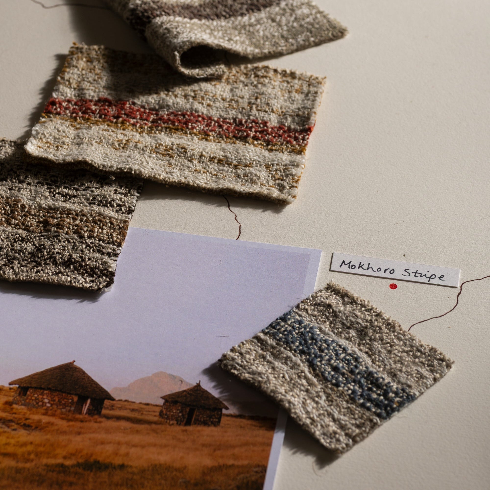 Textured fabric swatches on a surface with a landscape photo and label.