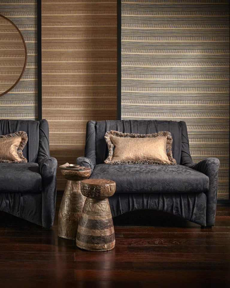 Two gray armchairs with decorative pillows in a room with striped walls.