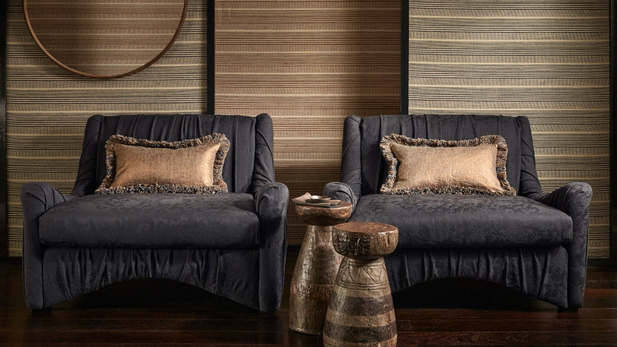 Two navy sofas with decorative pillows in a room with wooden walls and a wooden side table.