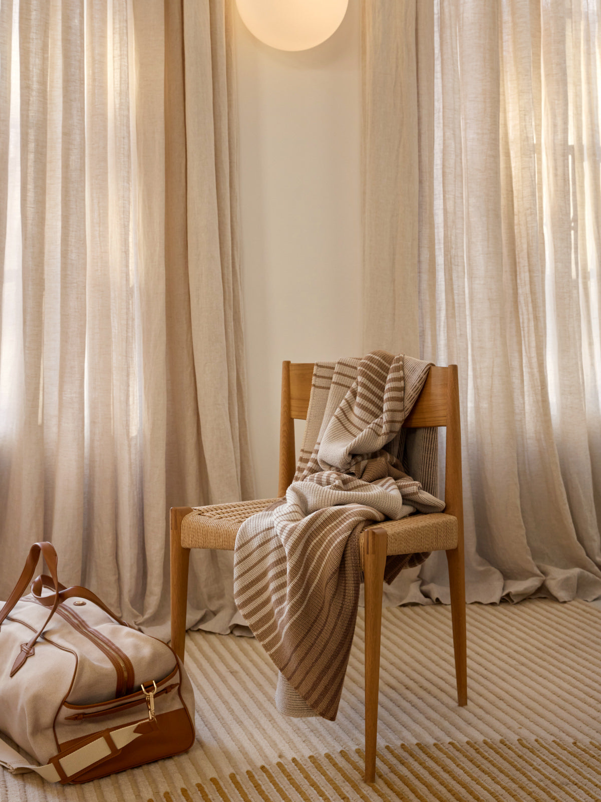 Wooden chair with a blanket draped over it against a curtain backdrop