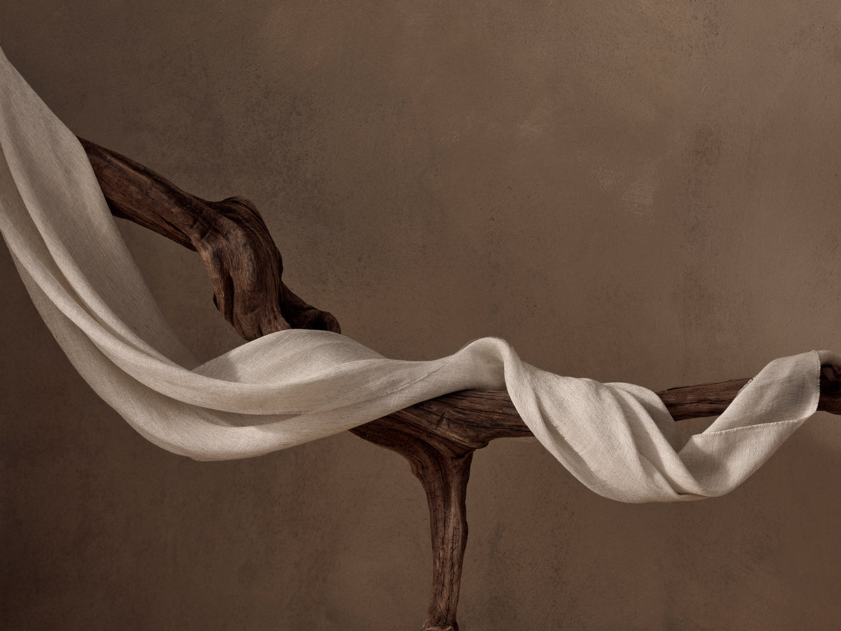 White fabric draped over a wooden branch against a brown background