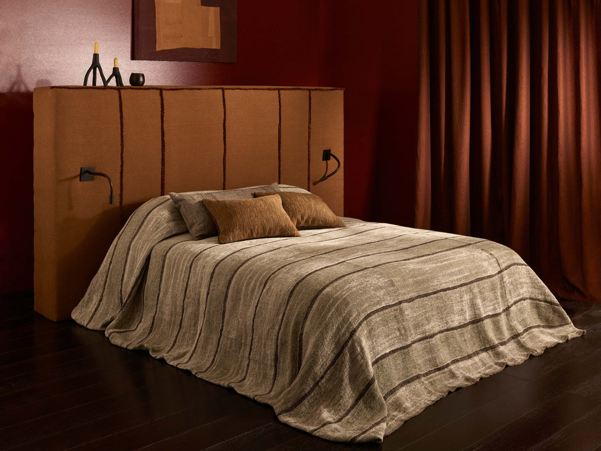 Textured neutral bed linen, rust headboard and brown curtains in a warm red bedroom.
