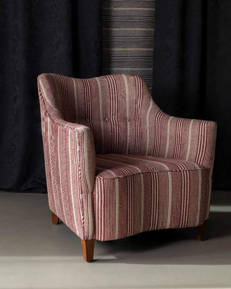 Striped armchair against a dark curtain backdrop
